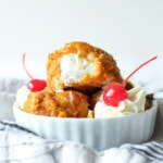 Helado frito con crema batida y cerezas.