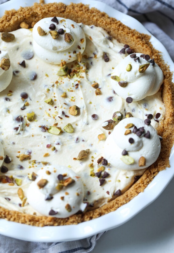 Pastel de cannoli en un molde para pastel cubierto con crema batida y pistachos