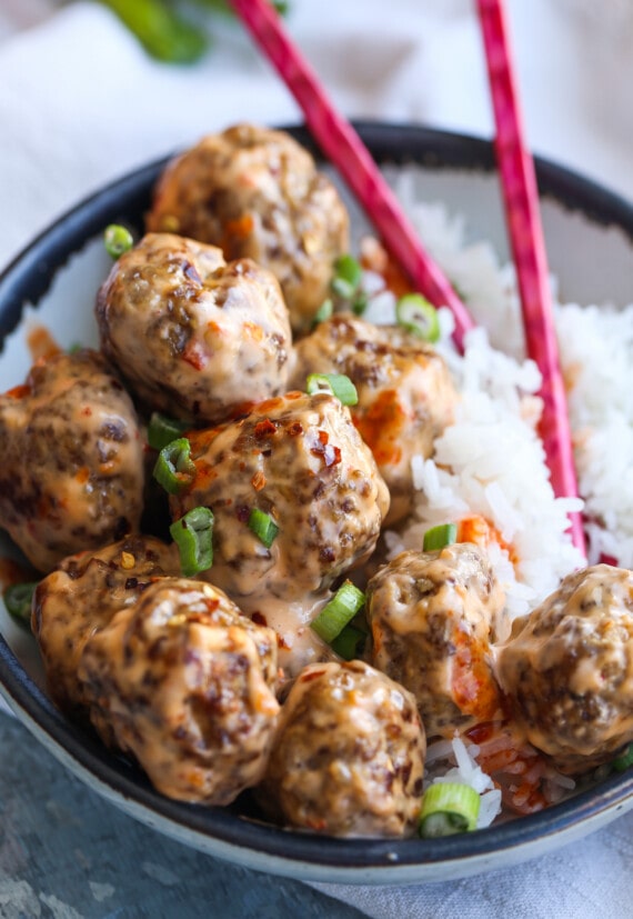 Un tazón de albóndigas bang bang con palillos y arroz.