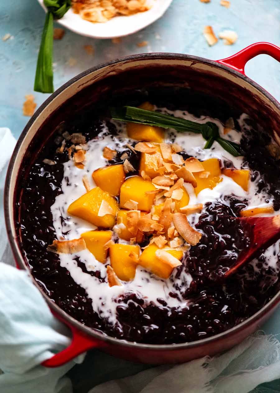 Pudín de arroz pegajoso negro tailandés en bote con mango y coco