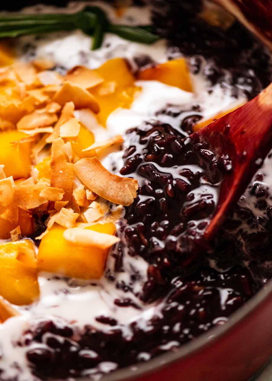 Cerca de tailandés con pudín de arroz pegajoso negro en una olla con mango