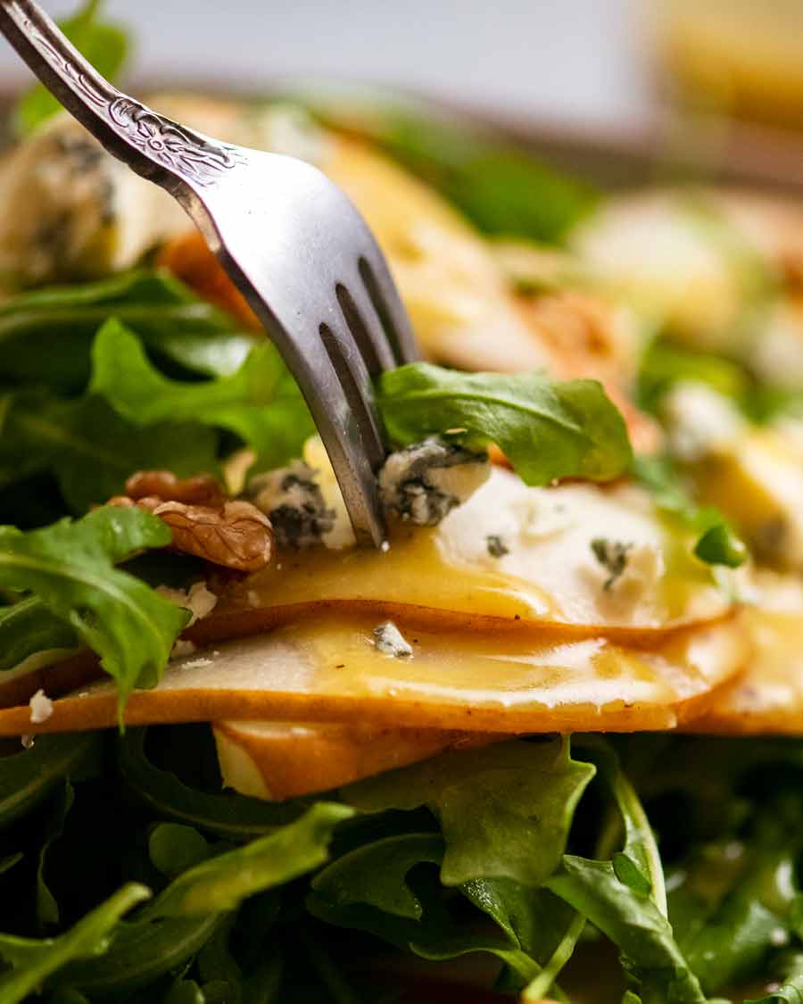 Tenedor recogiendo ensalada de peras con queso azul y rúcula rúcula