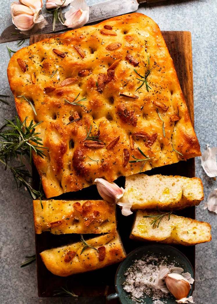 Fotografía aérea de Focaccia de ajo y romero sobre una tabla de madera, lista para ser servida