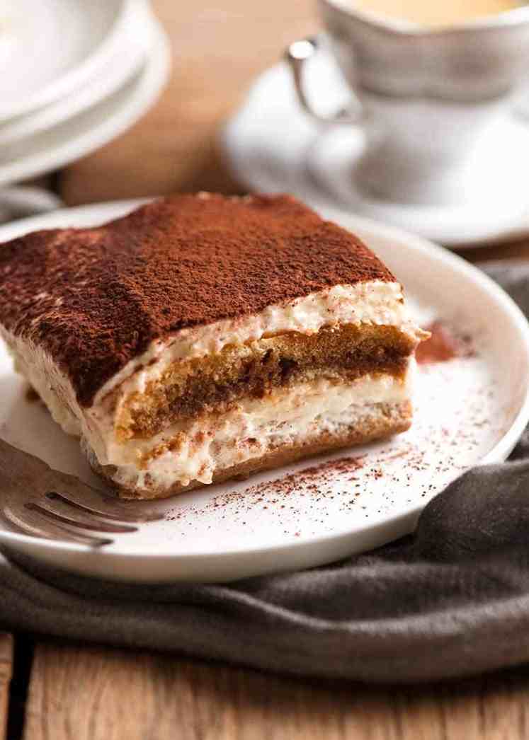 Cerca de una rodaja de tiramisú en una placa blanca, listo para ser comido