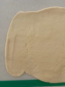 Masa de pizza extendida sobre un banco