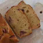 Un pan de plátano y fresa con dos rebanadas cortadas mostrando fresas horneadas en su interior.