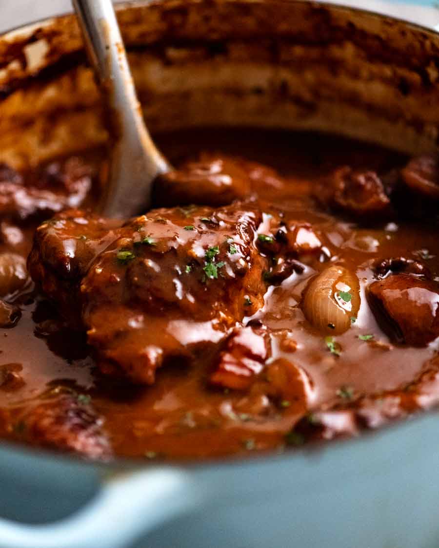 Sirviendo Coq au Vin recién cocido - estofado de pollo francés