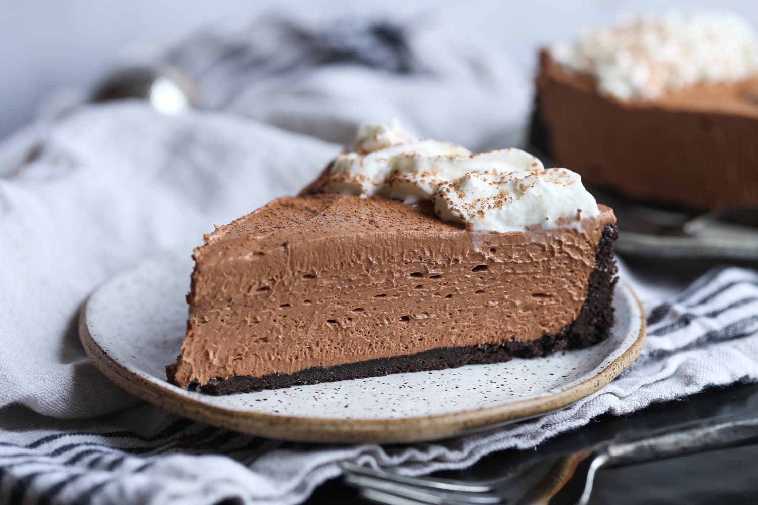 Una rebanada de tarta de queso de Nutella con costra de Oreo y nata montada.
