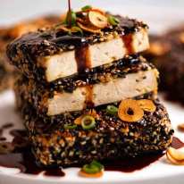 Rociar salsa teriyaki sobre filetes de tofu con costra de sésamo con salsa teriyaki