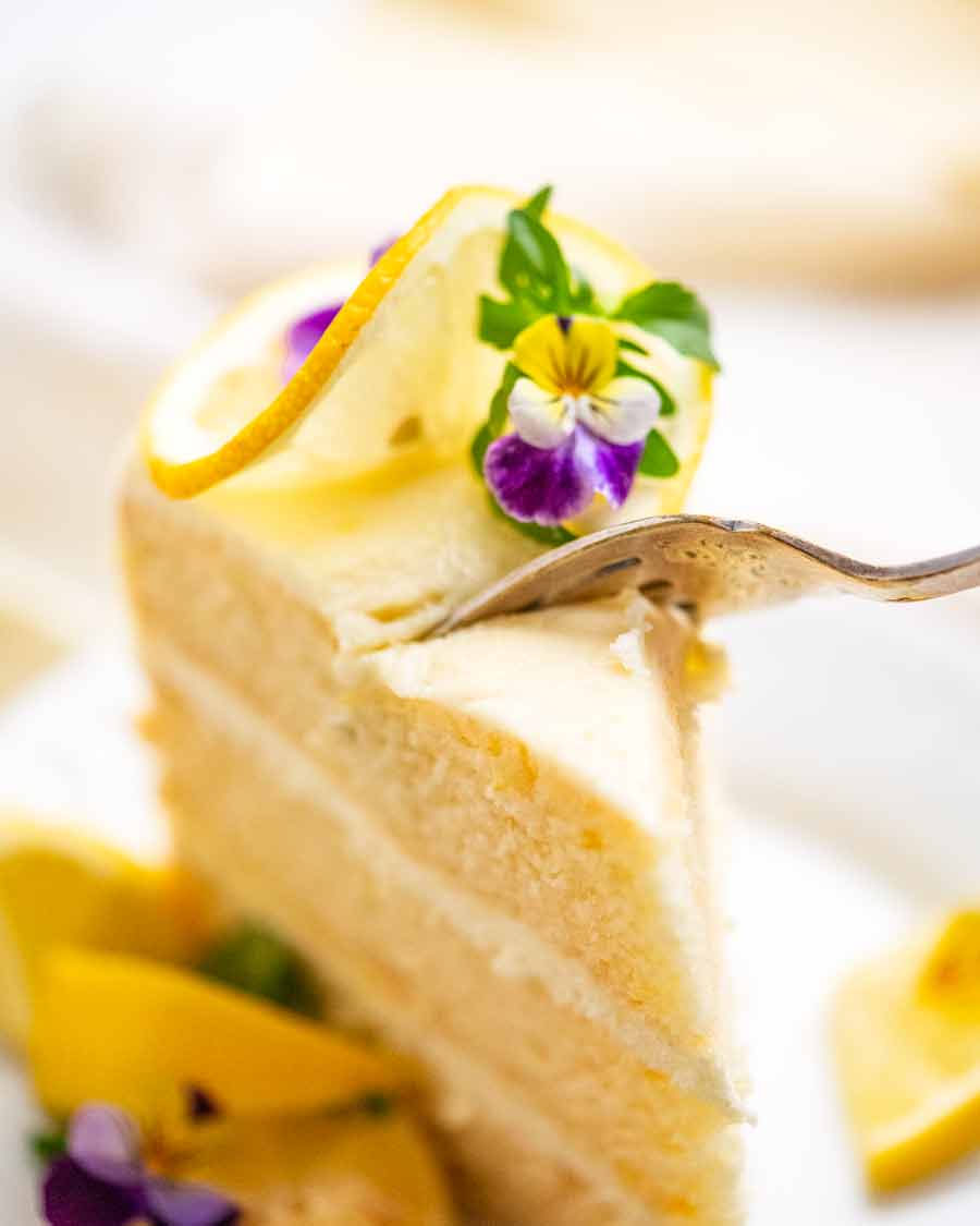 Cortar con un tenedor un trozo de pastel de limón con glaseado de limón esponjoso