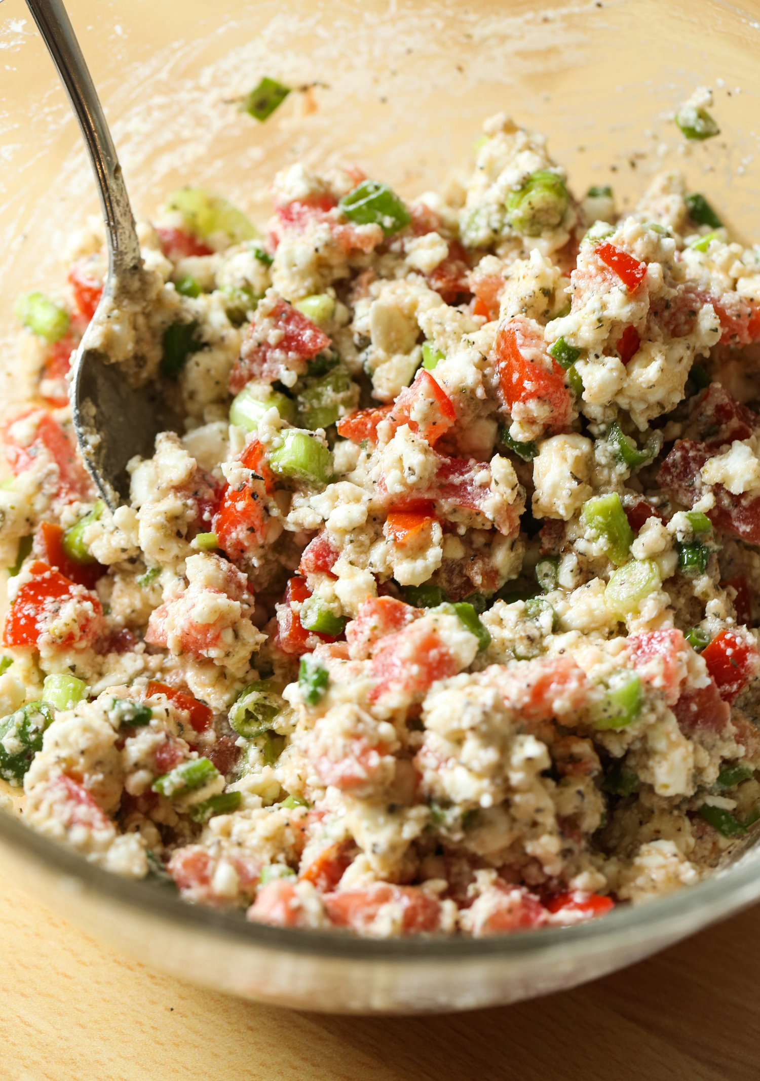 Queso feta, cebollas verdes, tomates y condimentos en un bol