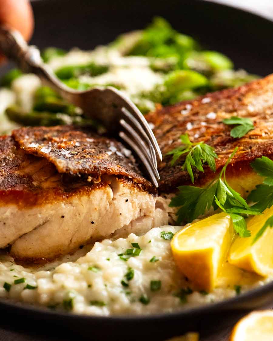 Barramundi de piel crujiente servido con un sencillo risotto cremoso de limón sin revolver