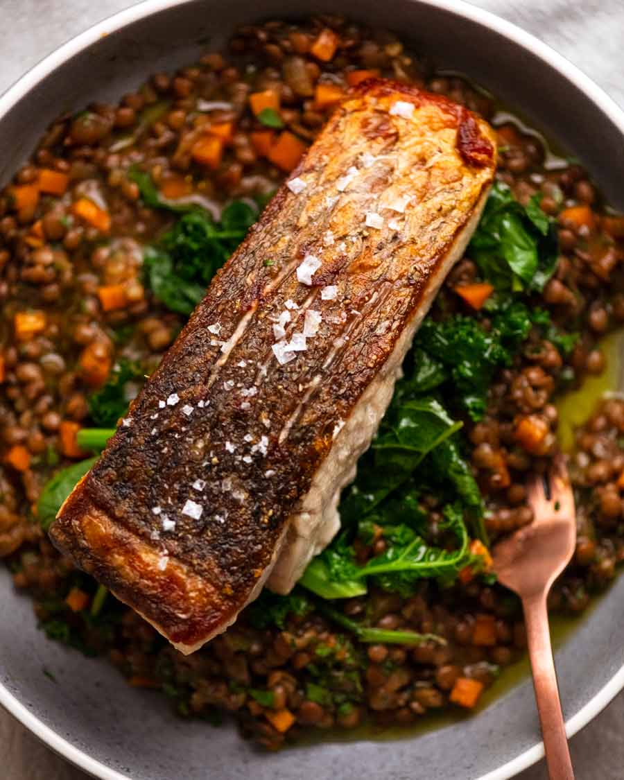 Barramundi de piel crujiente servido con una guarnición de ragu de lentejas francesas