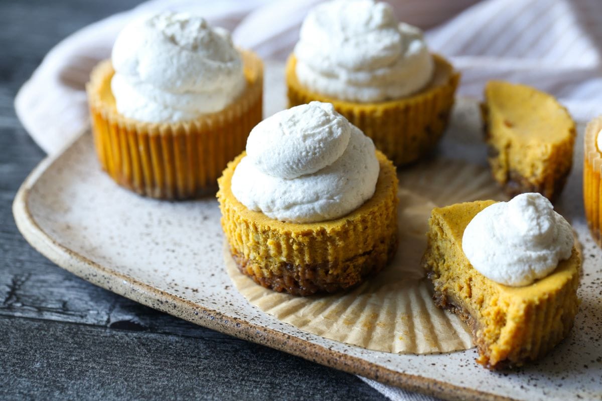 Mini tartas de queso de calabaza en una bandeja para hornear, un corte abierto para revelar el medio.