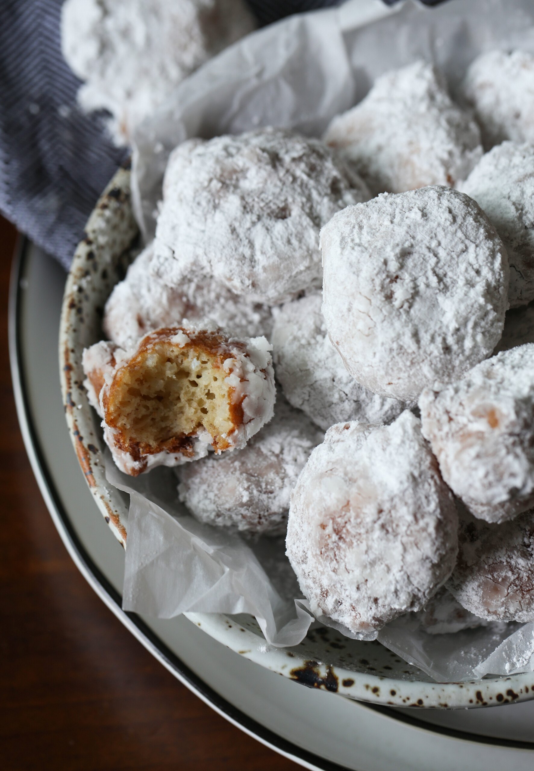 Sweet Calas en un recipiente recubierto de azúcar en polvo con un corte a la mitad mostrando el interior