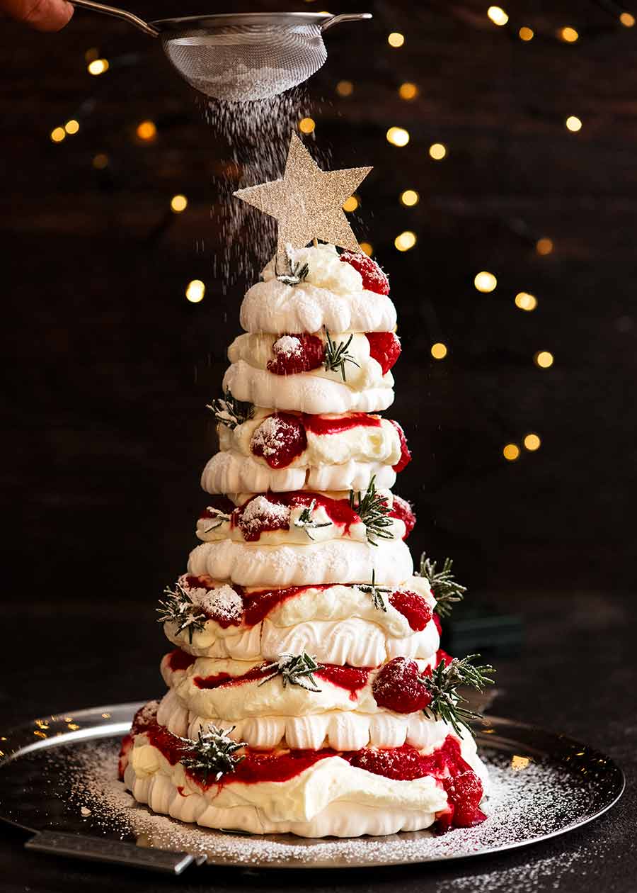 Espolvorear el postre de árbol de Navidad Pavlova con azúcar glas