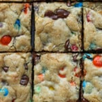 Barras de galletas M&M cortadas en cuadrados sobre una tabla de cortar desde arriba