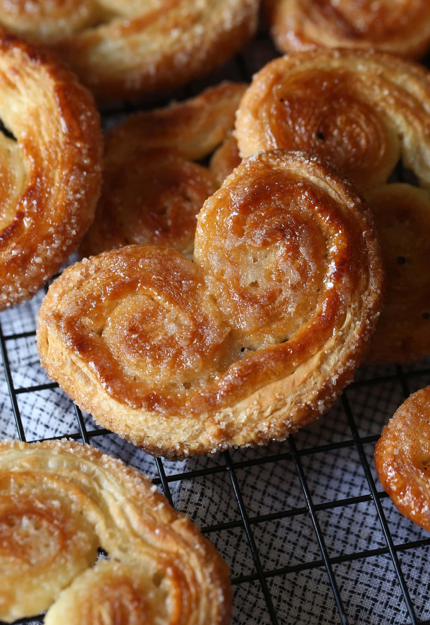 Galletas palmier crujientes y doradas esparcidas sobre una rejilla de alambre.