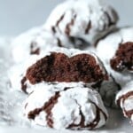 Galletas de chocolate arrugadas en un plato blanco, con una de las galletas rota por la mitad y los lados rotos hacia la cámara.