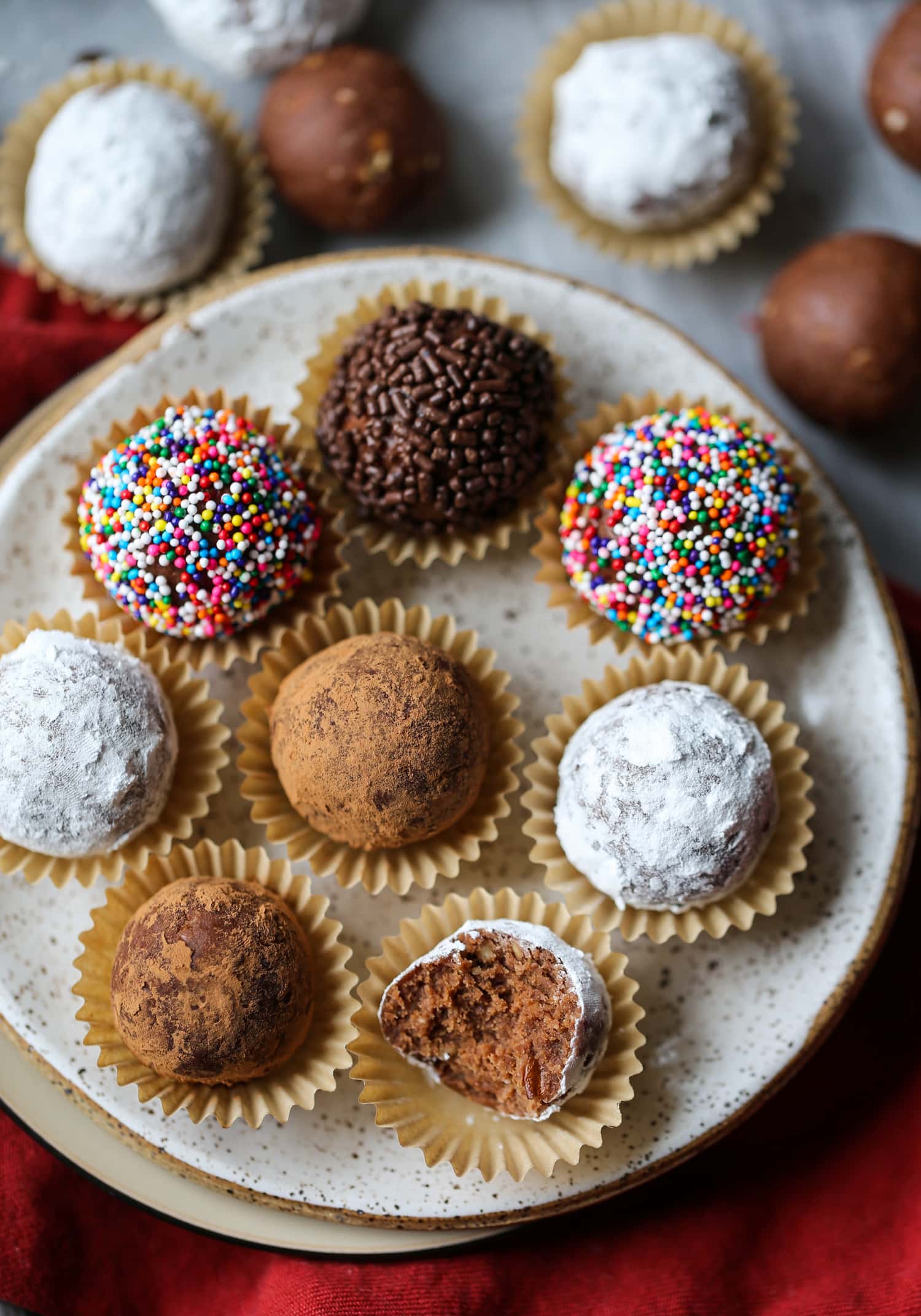 Bolas de ron navideñas decoradas en tazas de caramelo, dispuestas en un plato, a uno le falta un bocado.