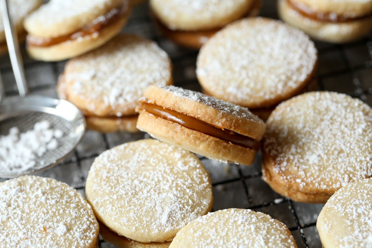 Galletas de alfajores espolvoreadas con azúcar glass, rellenas de dulce de leche.