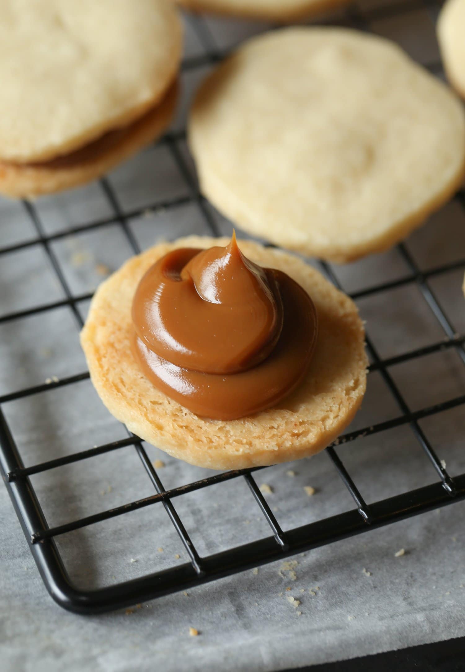 Una galleta alfajor de cara abierta con una cucharada de relleno de dulce de leche.