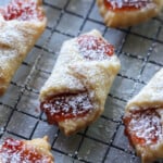 Un primer plano de las galletas kolaczki rellenas de confitura de fresa y espolvoreadas con azúcar en polvo.