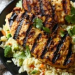 El pollo a la parrilla con mantequilla de maní se sirve sobre una cama de arroz y verduras.