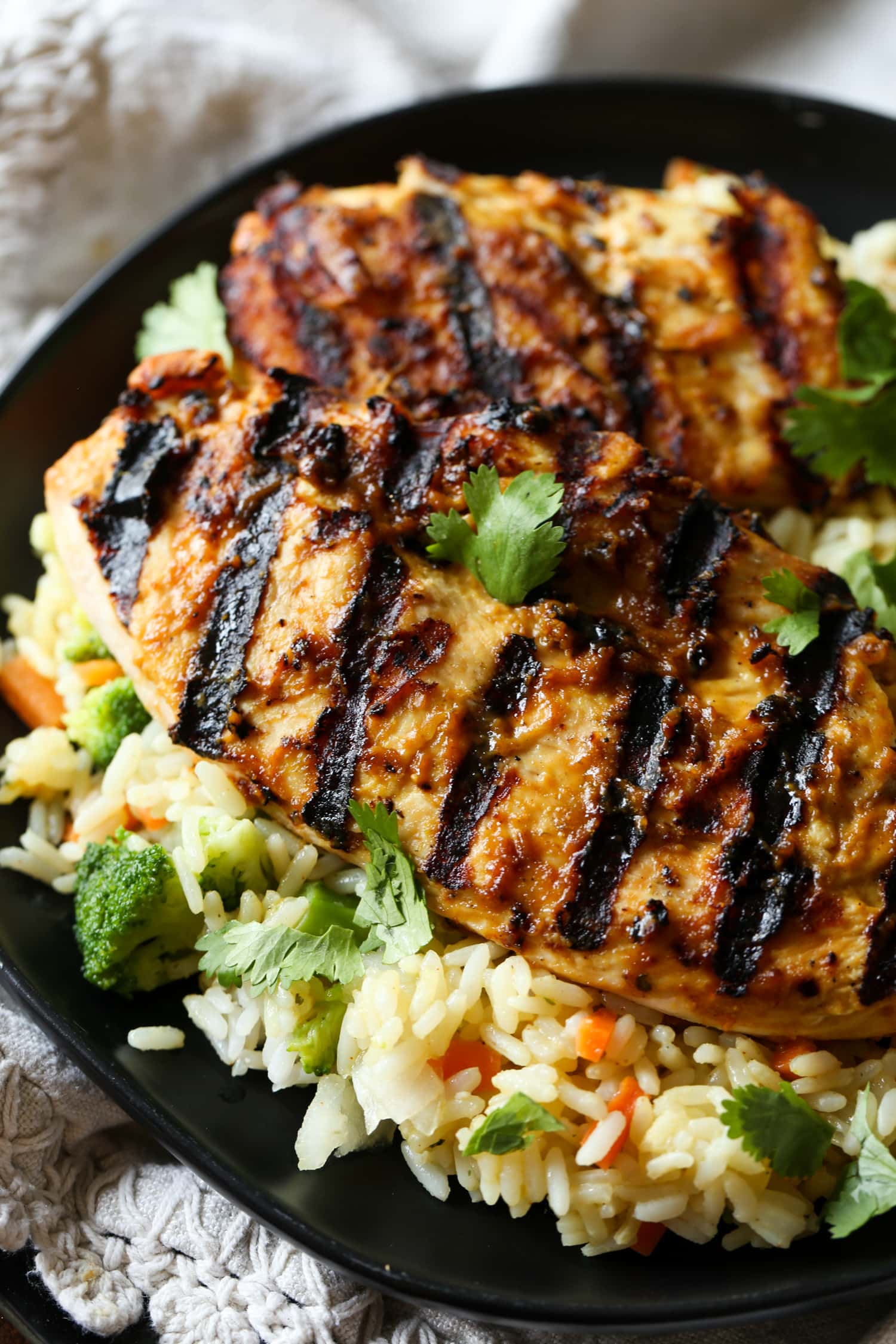 El pollo a la parrilla con mantequilla de maní se sirve sobre una cama de arroz y verduras.