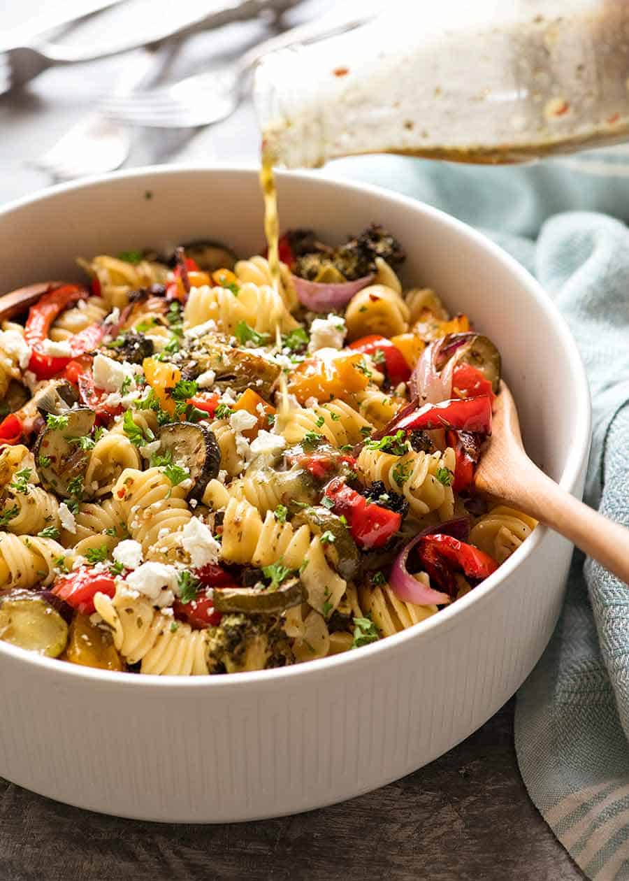 Verter el aderezo de ensalada de pasta con limón y ajo sobre la ensalada de pasta con verduras