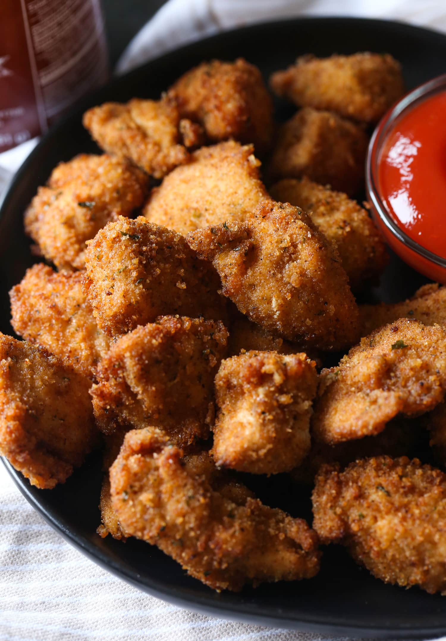 Nuggets de pollo caseros picantes en un plato junto a la salsa para mojar.