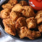 Nuggets de pollo picantes en un plato junto a un tazón de salsa picante para mojar.