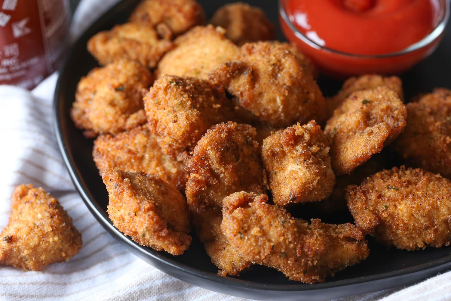 Nuggets de pollo picantes en un plato junto a un tazón de salsa picante para mojar.