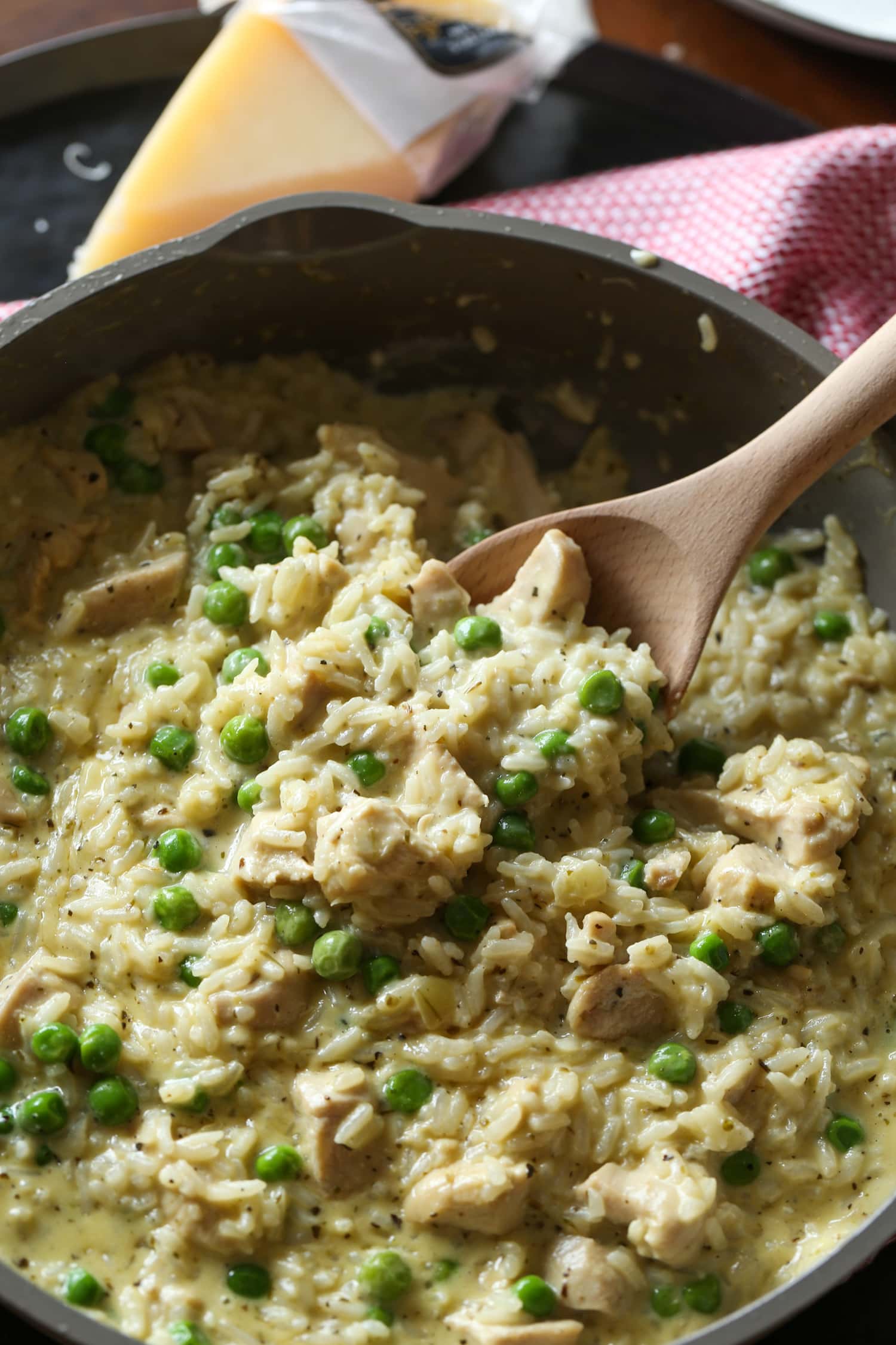 Se usa una cuchara de madera para sacar pollo cremoso y arroz de una olla.