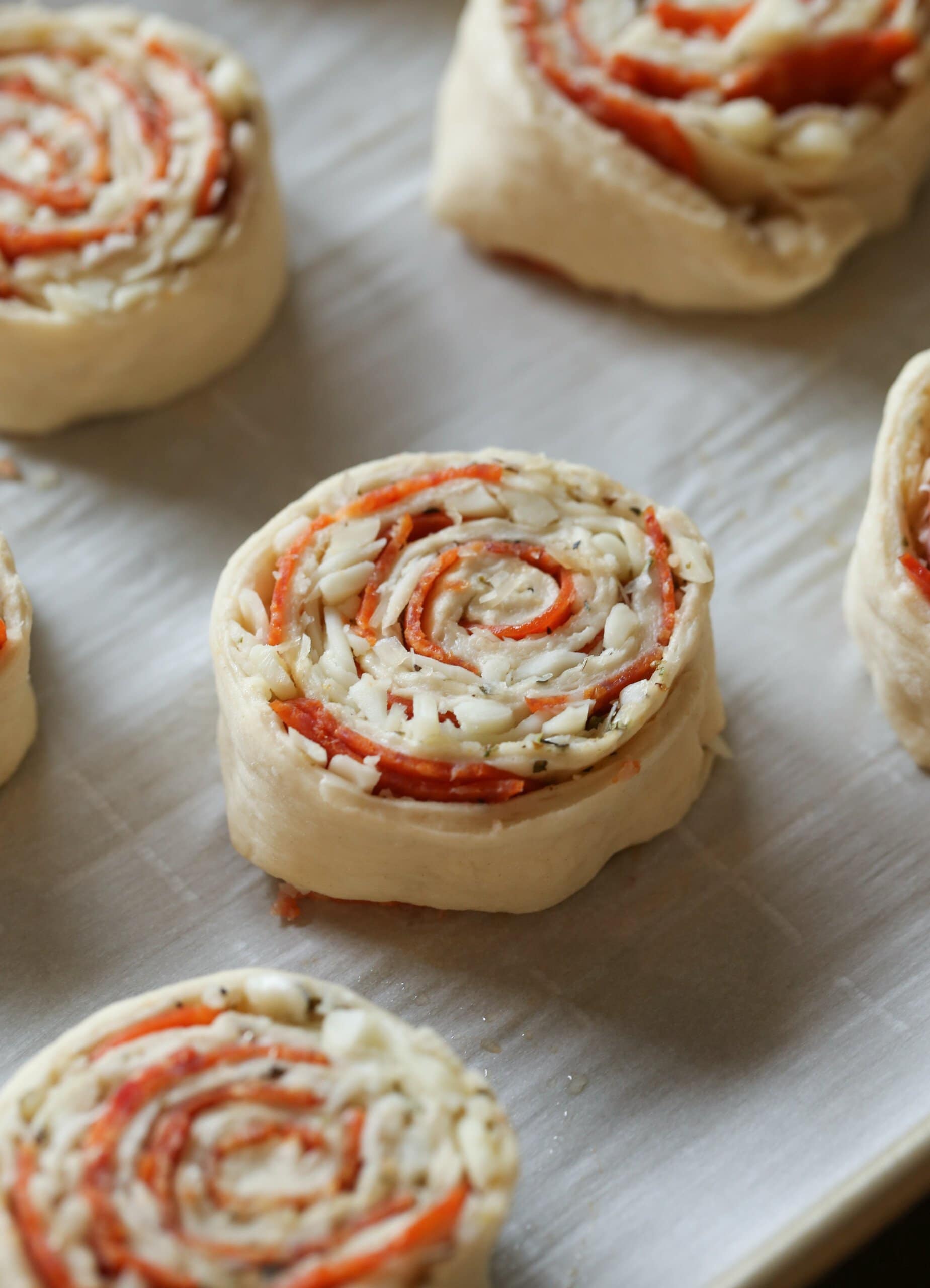 Rollos de pizza sin hornear colocados en una bandeja para hornear forrada de pergamino.