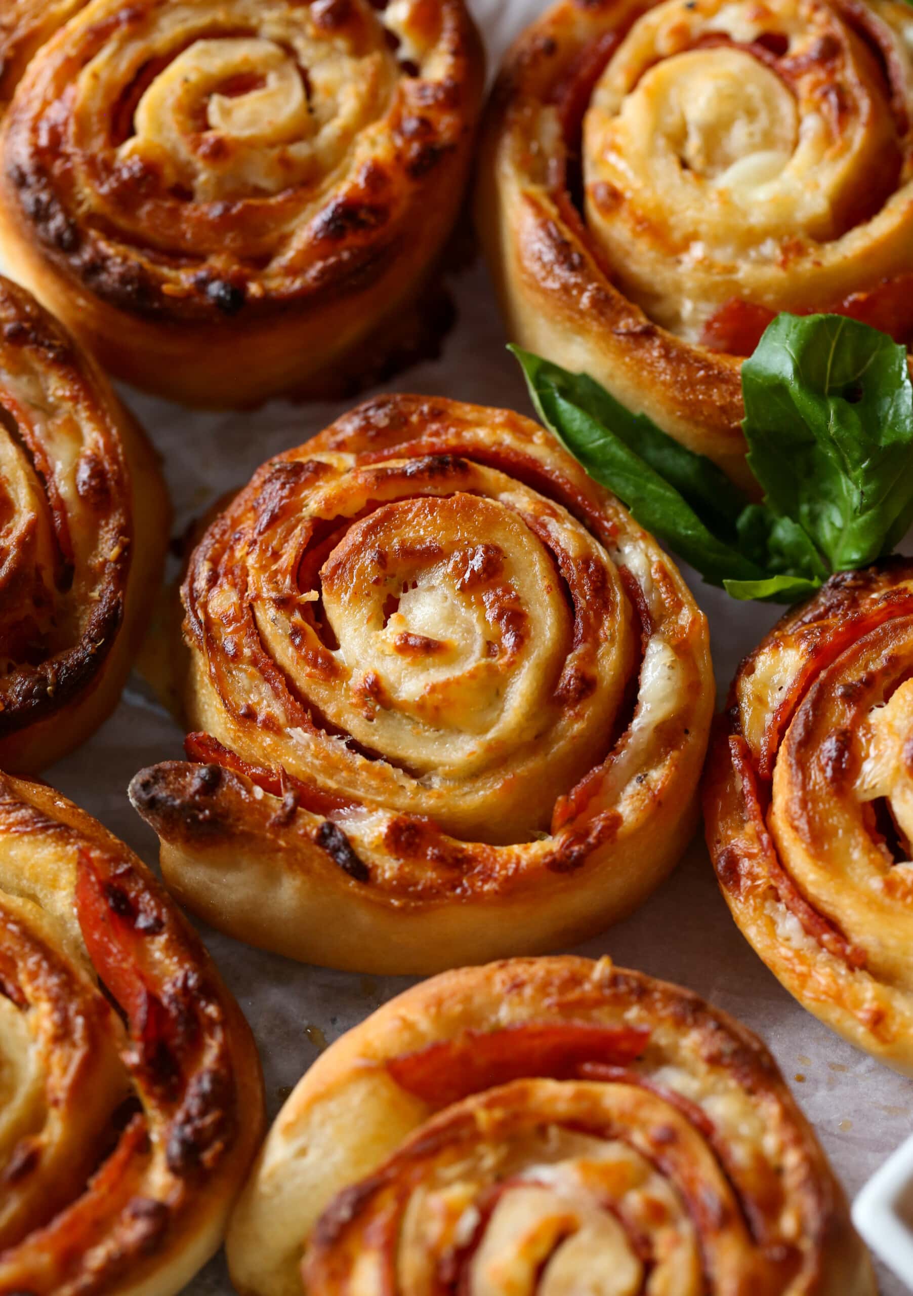 Rollos de pizza al horno con una guarnición de hojas de albahaca.