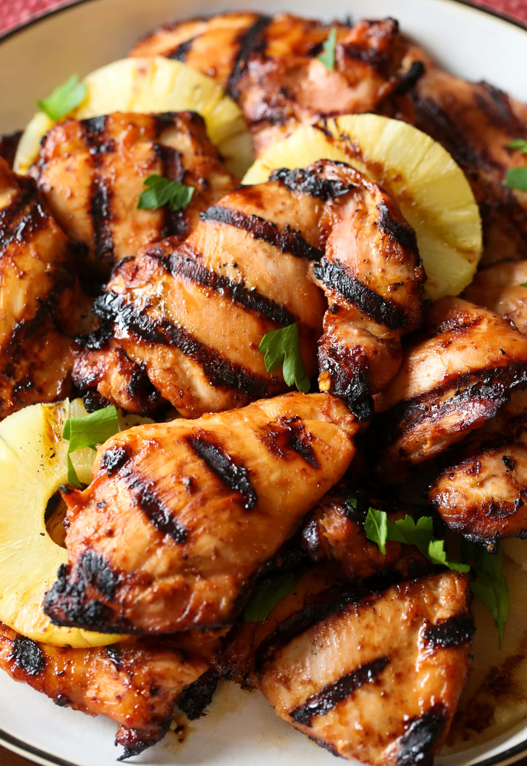 Muslos de pollo huli huli a la parrilla hawaiano con piña en un plato.