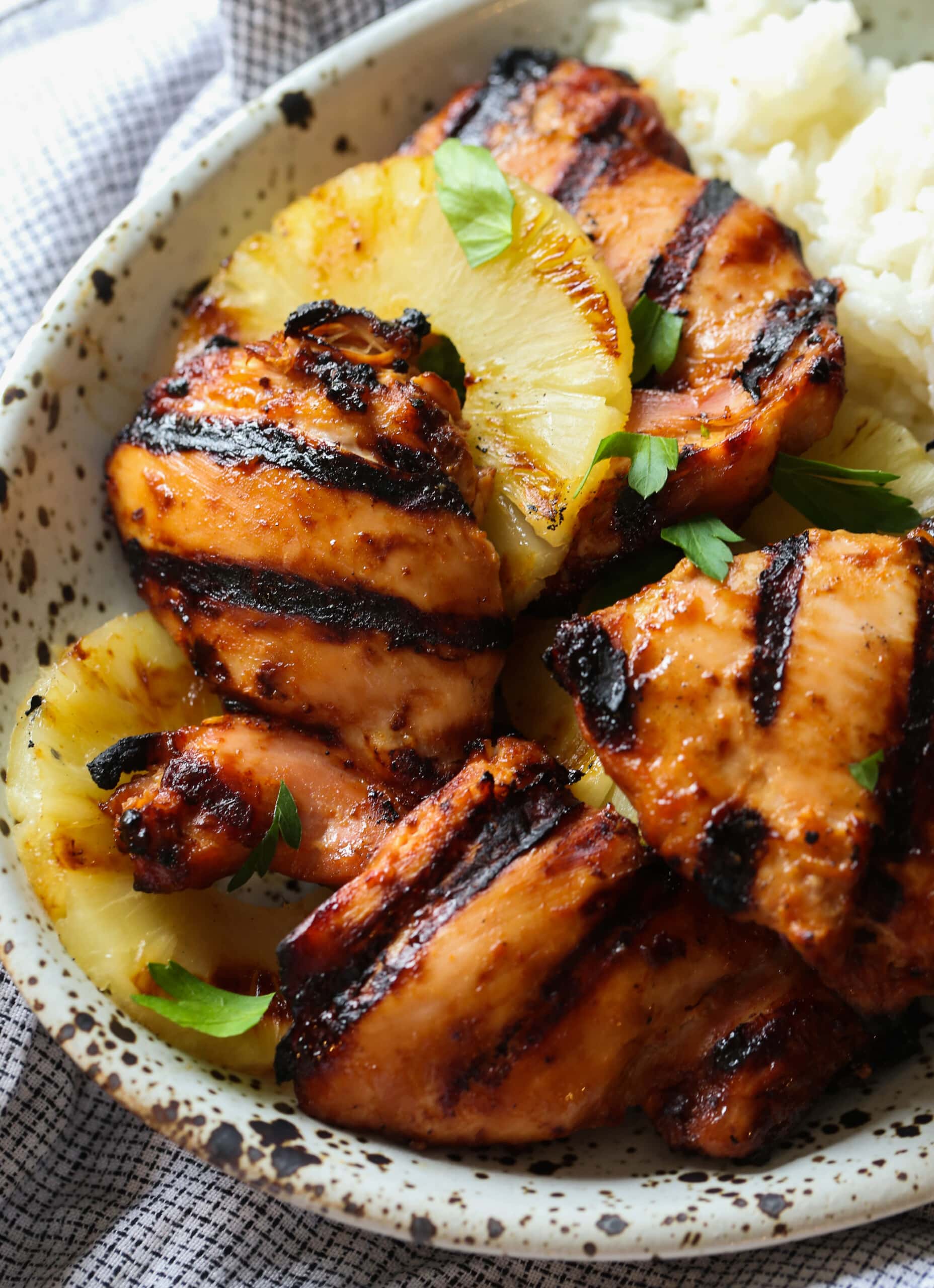 Pollo hawaiano Huli Huli servido en un tazón con piña asada sobre arroz.