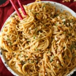 Un plato de fideos picantes de sésamo con palillos.