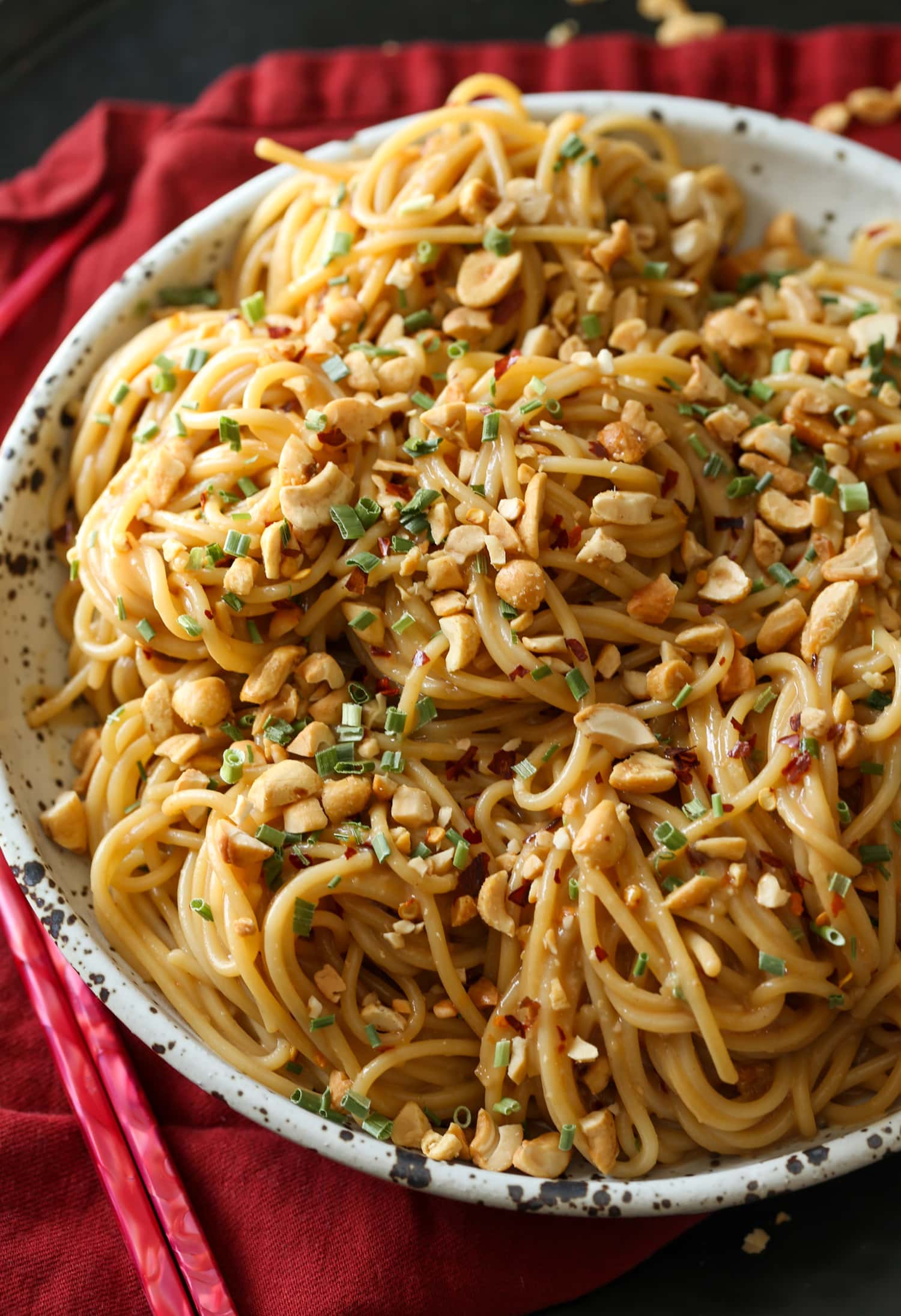 Un tazón de fideos de sésamo picantes cubiertos con cacahuetes triturados y cilantro.
