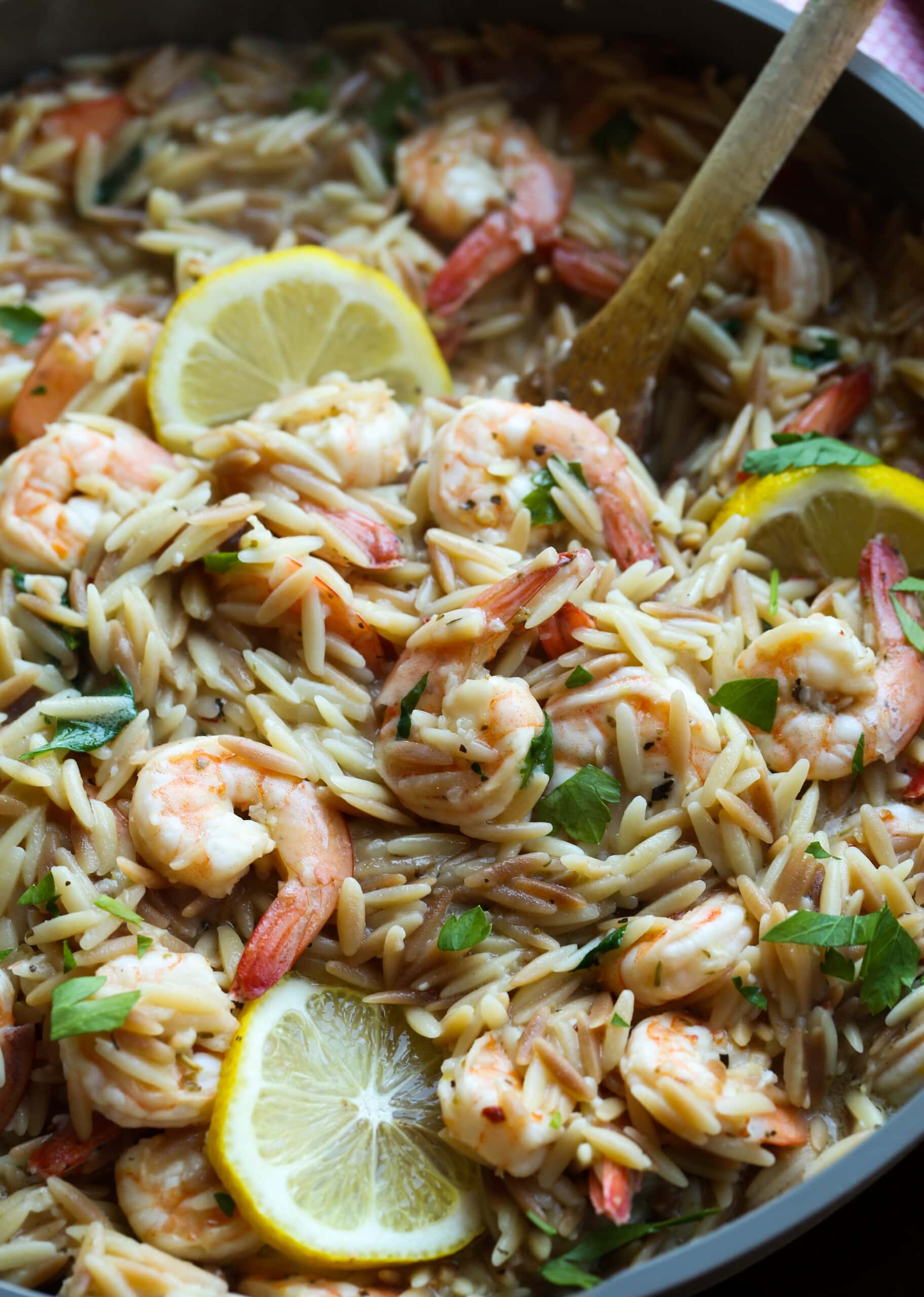 Camarones orzo en una sartén con limones.
