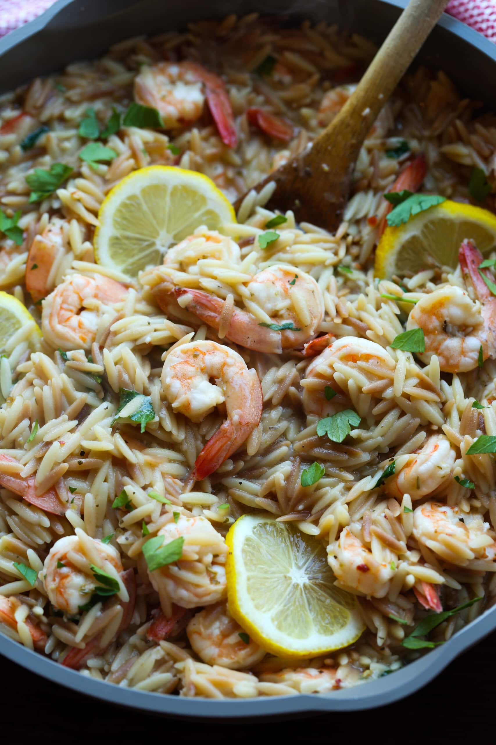 Camarones orzo en una sartén con limones.