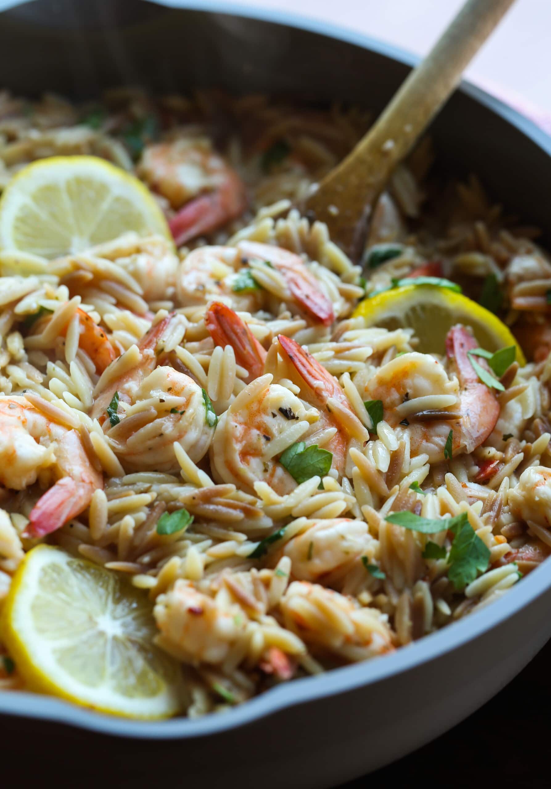 Camarones orzo en una sartén con limones.