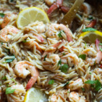 Camarones orzo en una sartén con limones.