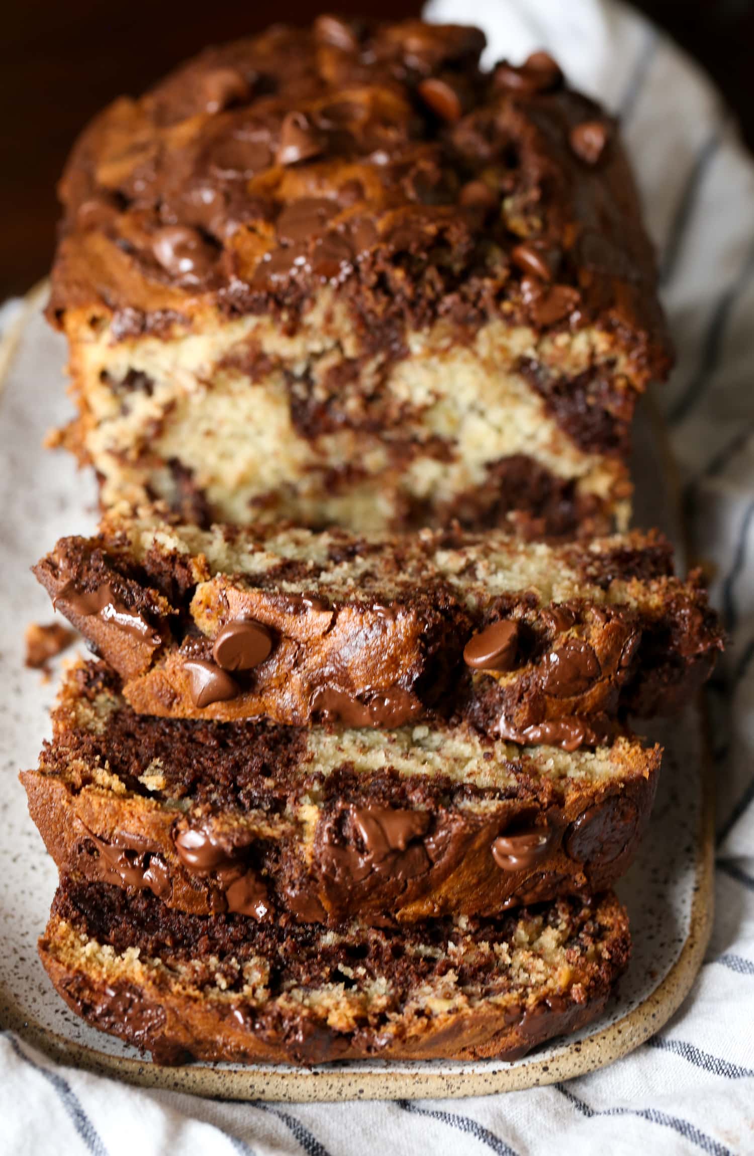 Una hogaza de pan de plátano marmoleado con chocolate cortado en rodajas para revelar el interior marmolado.