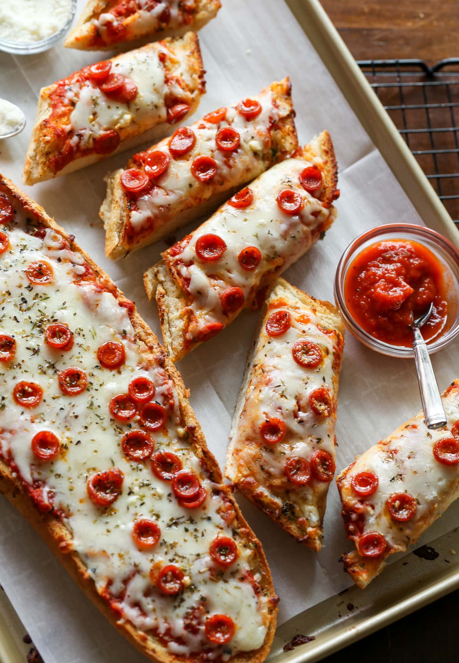 Pizza de pan francés cortada en rebanadas individuales en un plato, junto a las salsas para mojar.