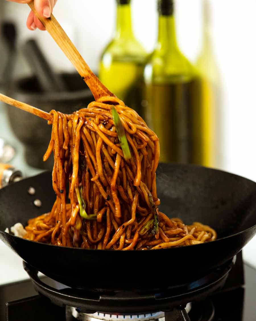 Tirar fideos asiáticos en un wok