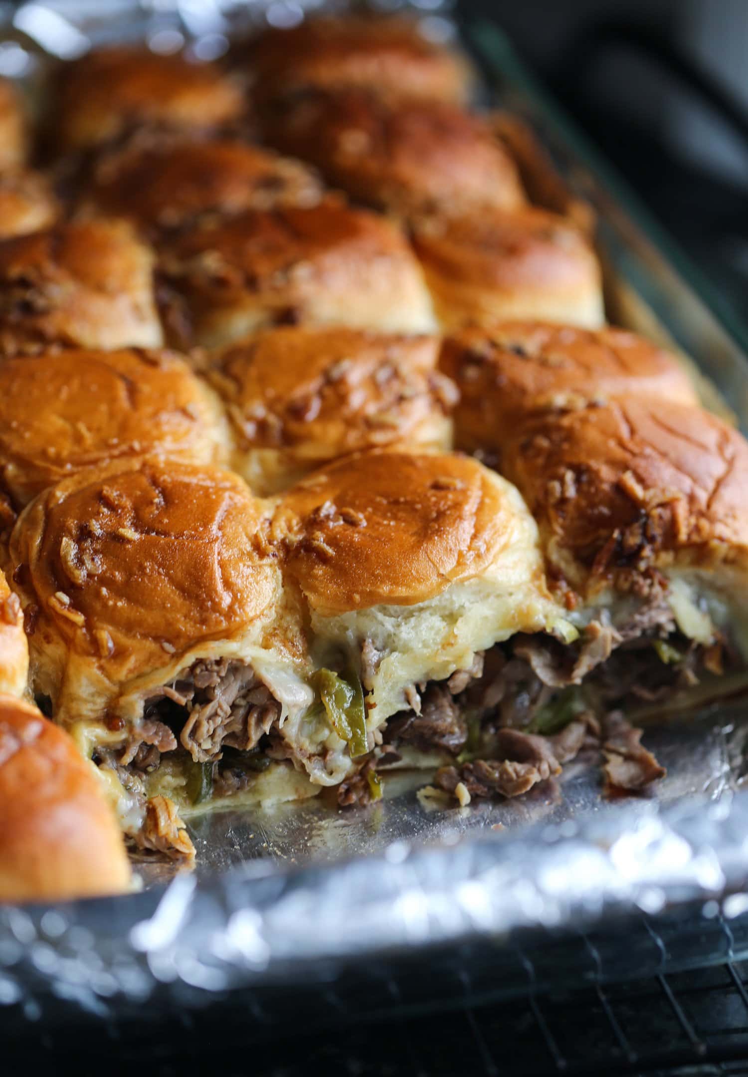 Deslizadores de bistec con queso Philly en una fuente para horno a la que le falta una fila.