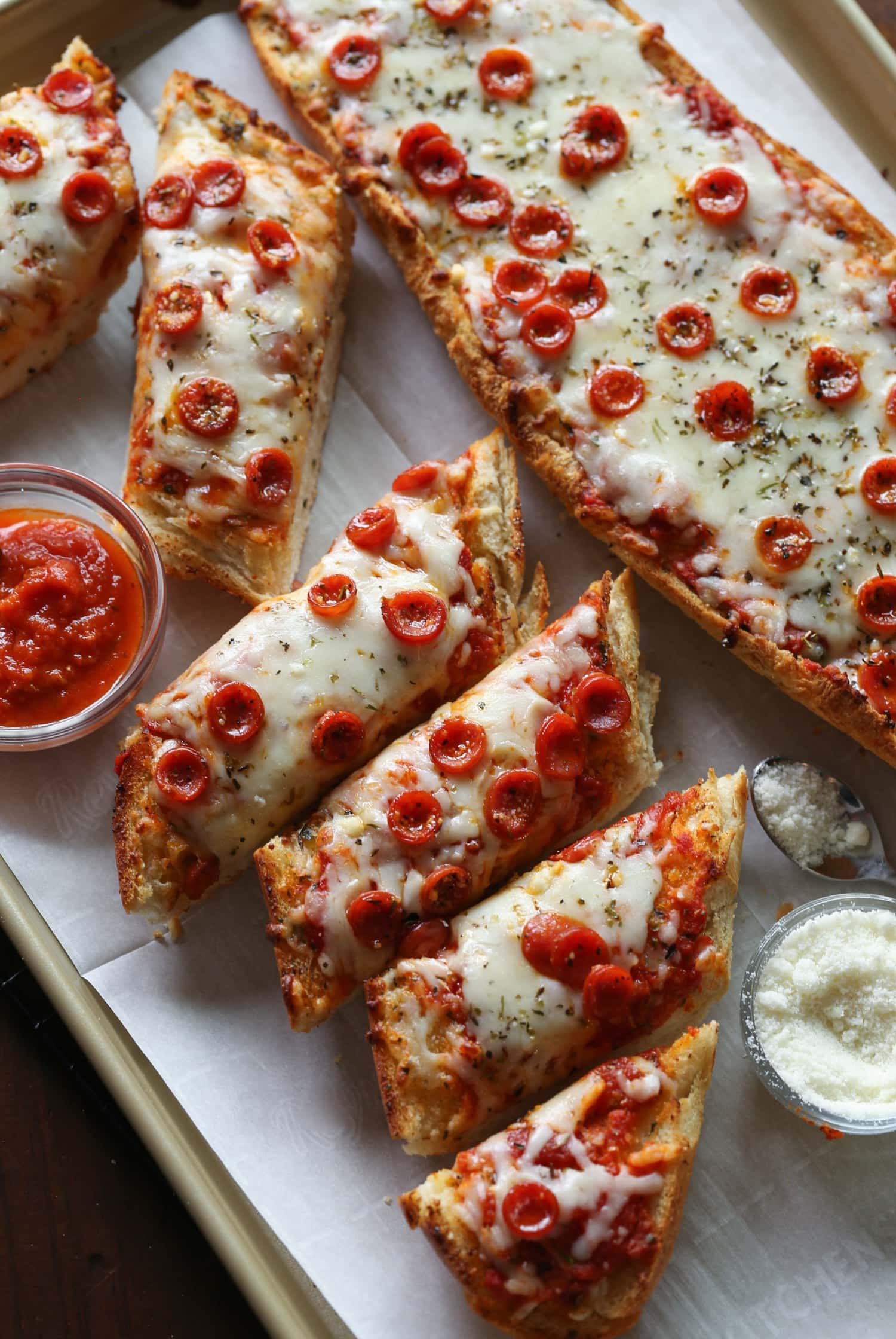Pizza de pan francés cortada en rebanadas individuales en un plato, junto a las salsas para mojar.