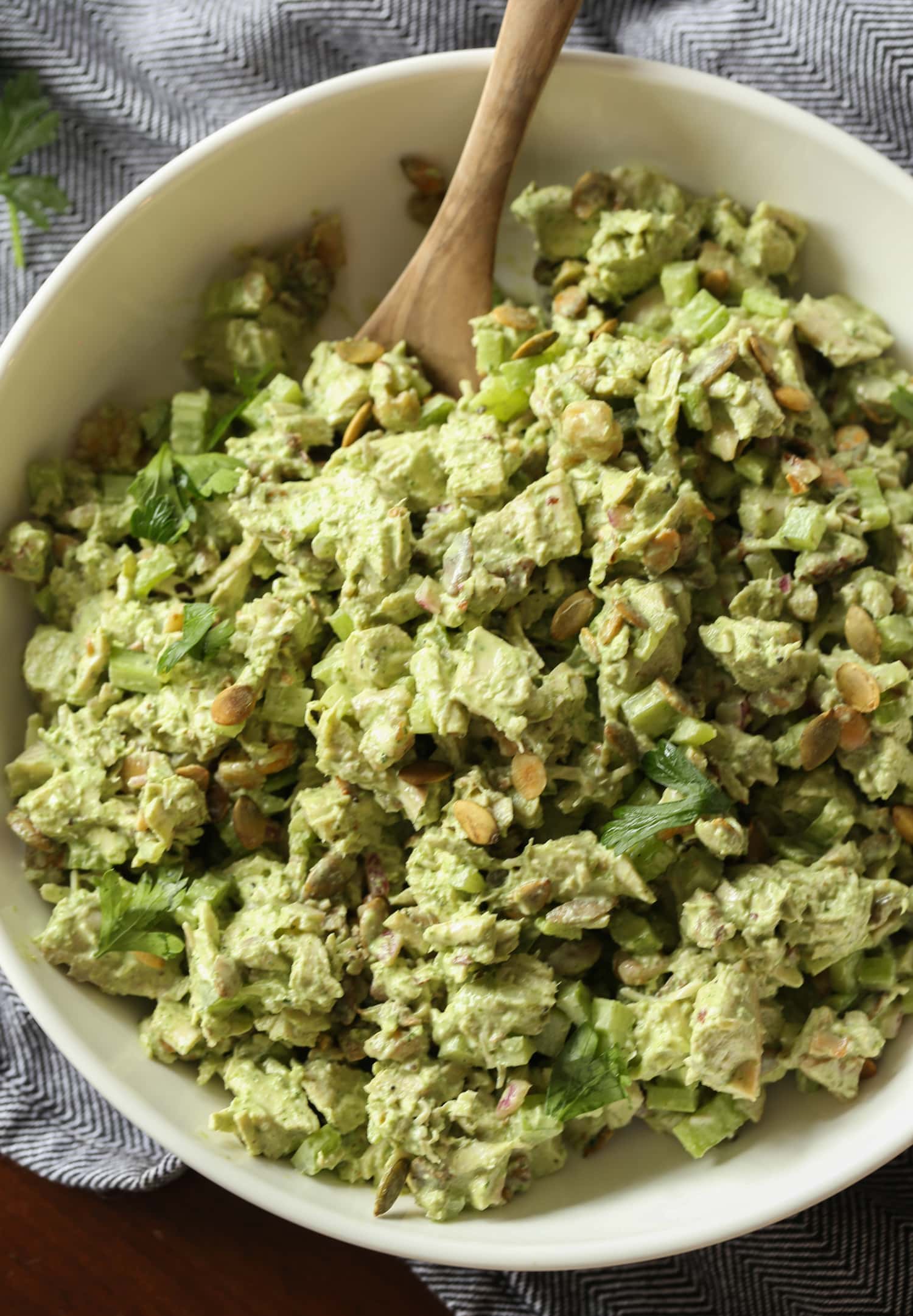 Ensalada de pollo diosa verde en un tazón grande con una cuchara de madera.
